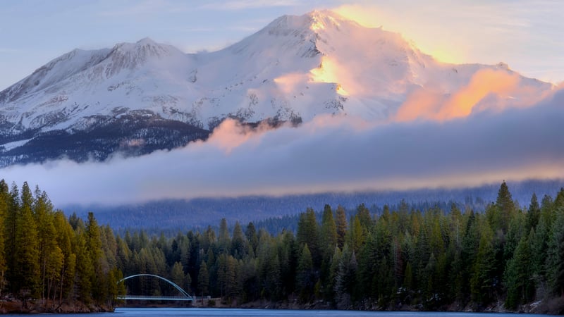 Snow-capped mountain peak with clouds and forest