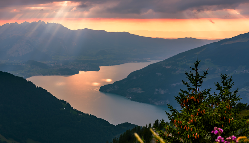 Sun rays over mountains and lake at sunset