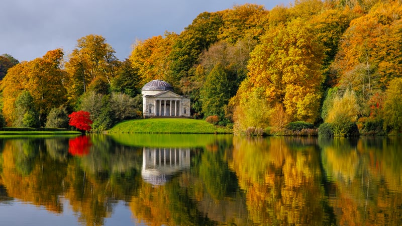 Temple reflected in a lake surrounded by autumn trees