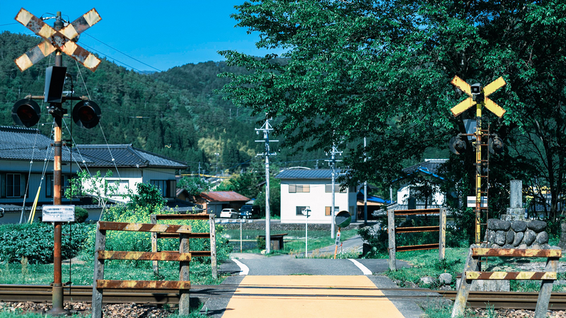 Railway crossing with houses and mountains