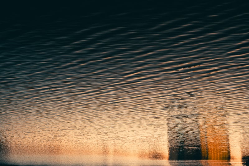 Reflection of buildings on rippling water at sunset