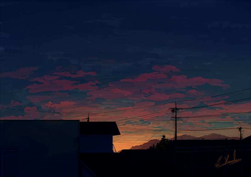 Sunset over rooftops with mountains and power lines