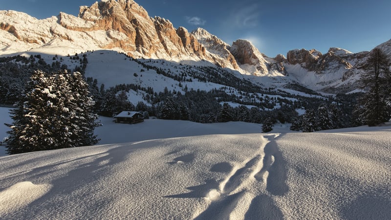 Snowy mountain peaks at sunset with footprints in the snow