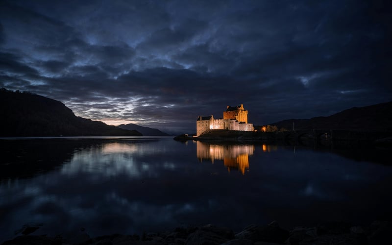 Castle illuminated at night reflected in a lake