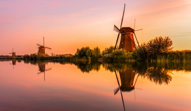 Windmills reflected in water at sunrise