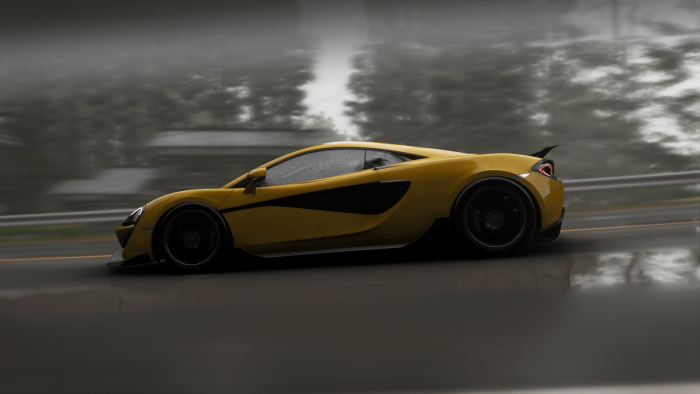Yellow McLaren sports car driving on a wet road