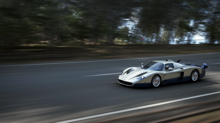 Silver and blue Maserati MC12 driving on a road