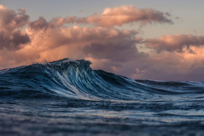 Ocean Wave Curling Under a Sunset Sky