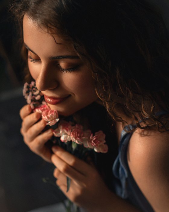 Young Woman Smiling and Smelling Pink Flowers
