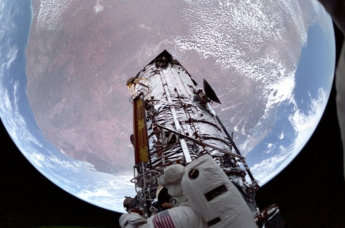 Astronaut Servicing the Hubble Space Telescope Over Earth