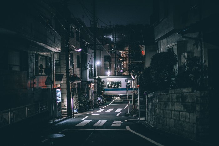 Narrow Japanese street at night with a passing train