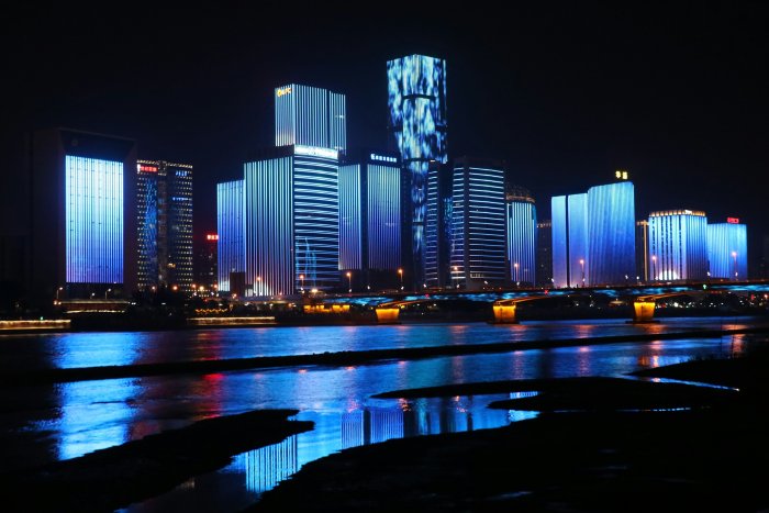 Illuminated blue skyscrapers reflecting on a river at night