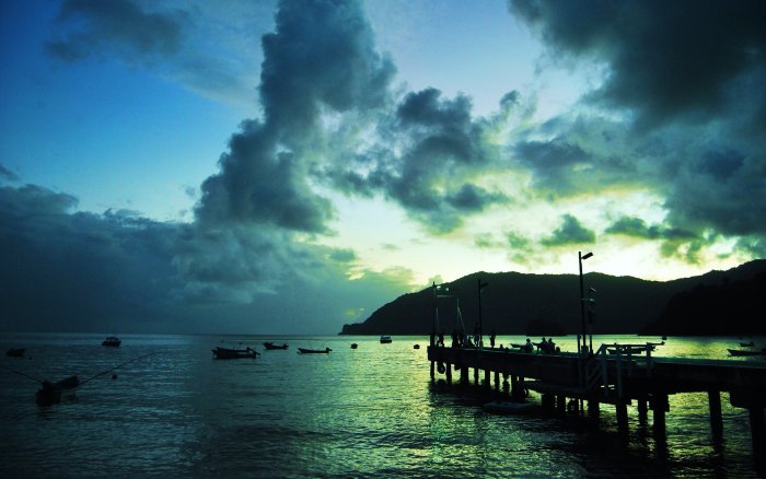 Wooden pier and boats on calm water under cloudy sky