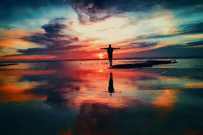 Silhouette of a person standing on a beach at sunset