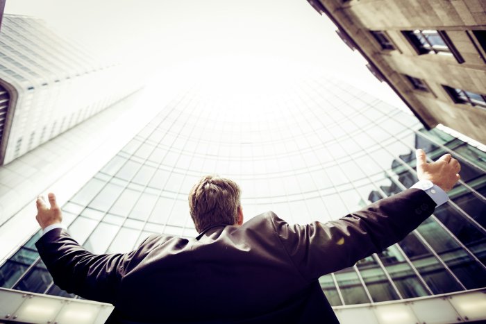 Man in Suit Looking Up at City Skyscrapers