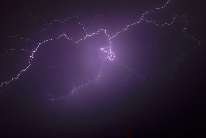 Purple lightning bolts flashing across a dark night sky
