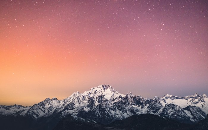 Snowy mountain range under starry gradient sky