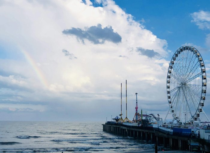 Amusement park pier with Ferris wheel under a rainbow