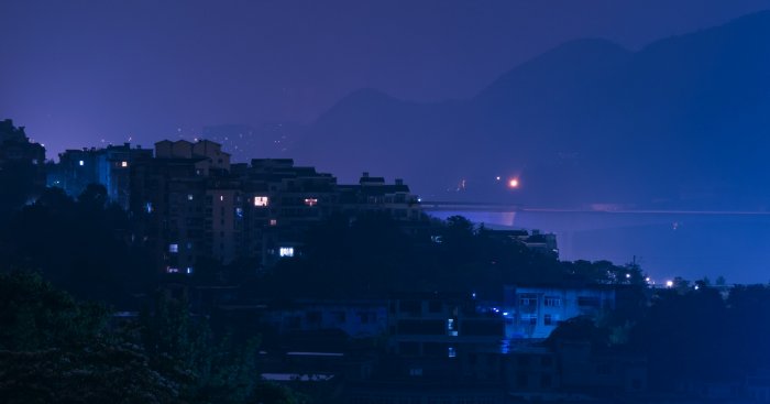 Hillside city buildings under a deep blue night sky