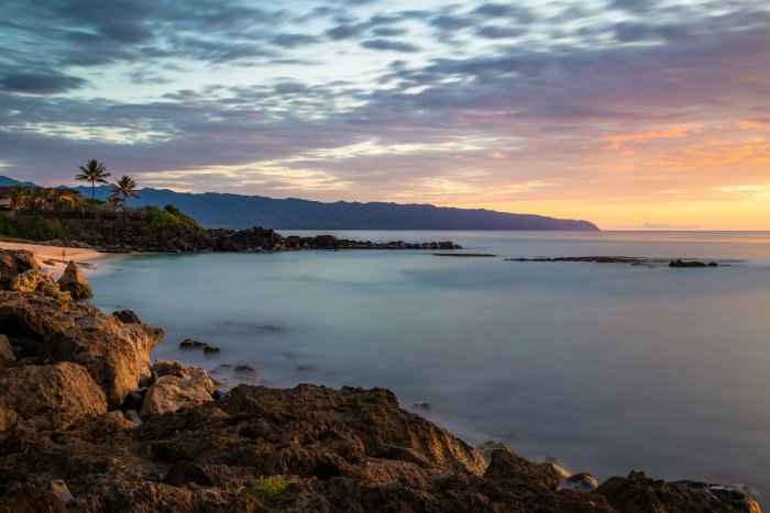 Rocky shoreline at sunset with distant mountains