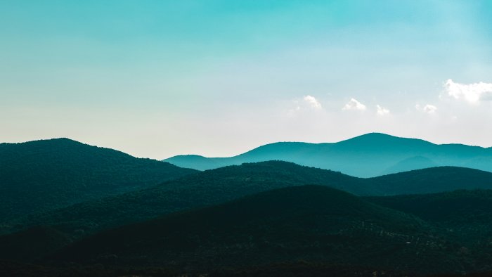 Layered green and blue mountain ridges under clear sky