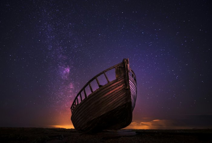 Abandoned wooden boat under the Milky Way galaxy