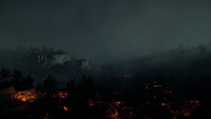 Dark misty valley with scattered lights at night