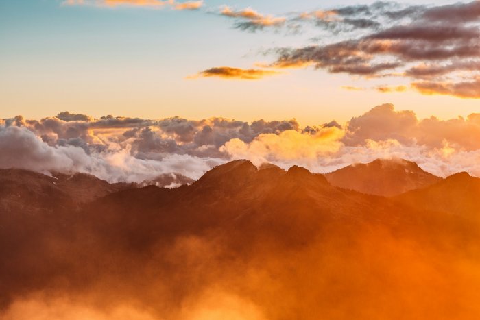 Mountain peaks above orange clouds at golden hour