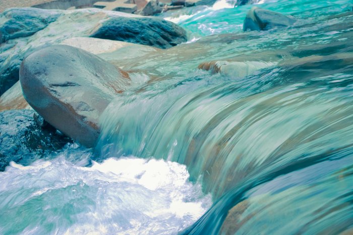 Smooth turquoise water flowing over river rocks