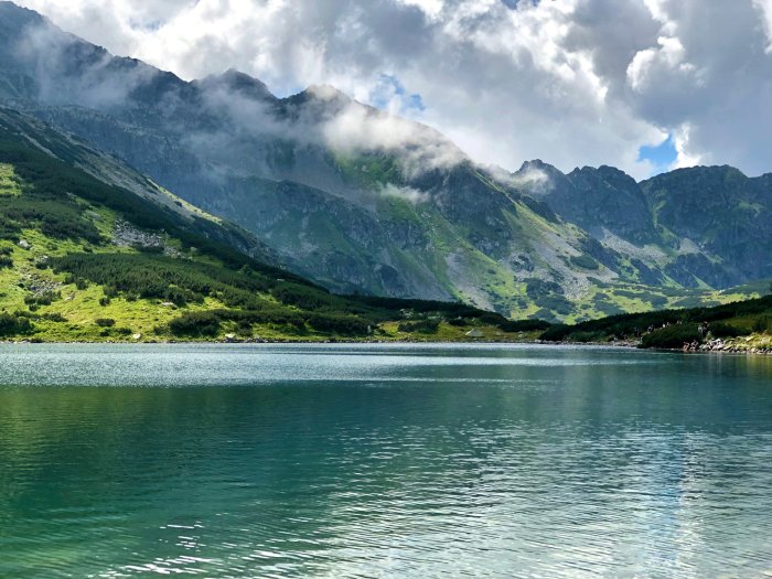 Mountain lake surrounded by green slopes and misty peaks
