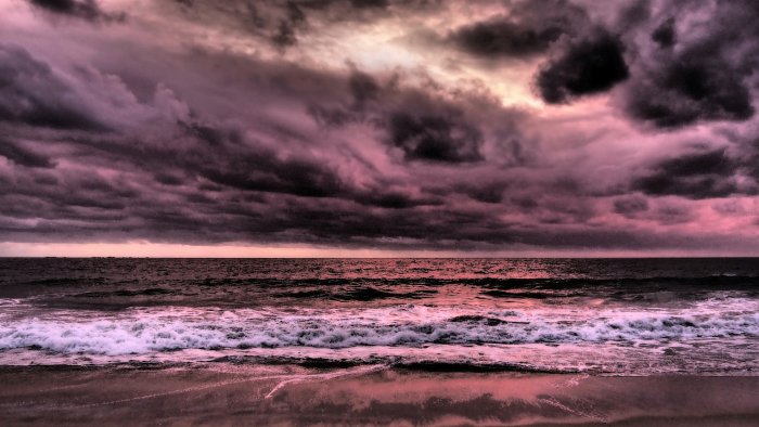 Dark pink storm clouds over ocean waves