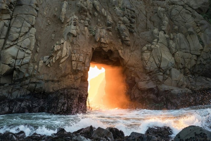 Golden light shining through a coastal rock arch