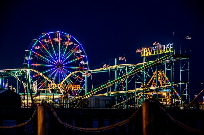 Illuminated Ferris Wheel and Roller Coaster at Night