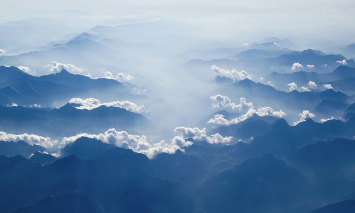 Aerial view of misty blue mountain peaks and clouds
