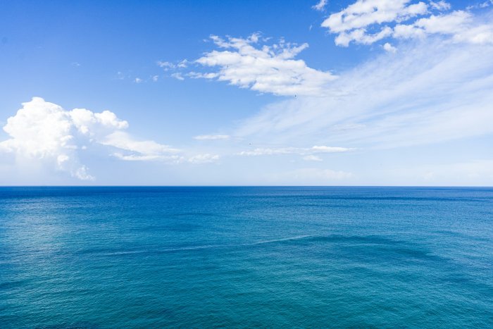 Blue sea under blue sky with white clouds