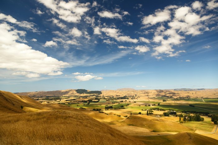 Golden rolling hills and countryside valley under blue sky