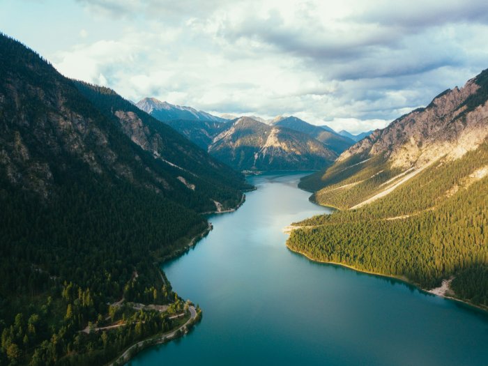 Turquoise lake winding between steep forested mountains