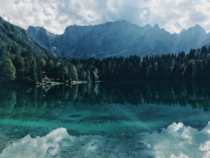 Clear turquoise alpine lake reflecting mountains and forest