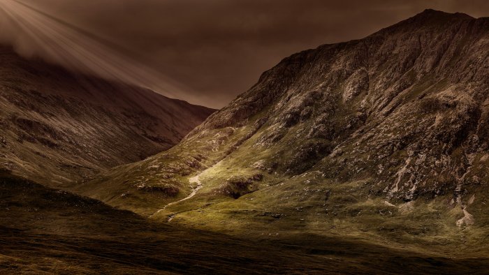 Sunlight breaking through clouds over a mountain valley