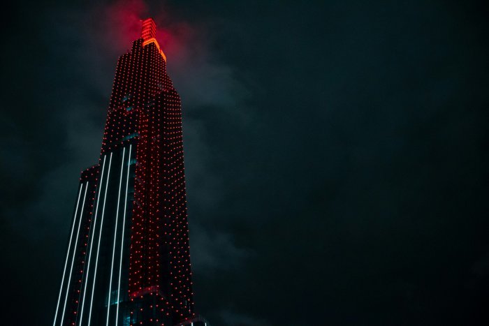 Tall skyscraper illuminated with red lights at night