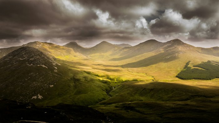 Green mountain valley under dramatic cloudy sky