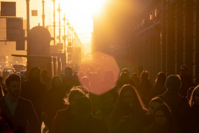 Crowd of people walking down a street at sunset