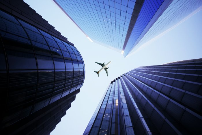 Airplane flying between modern skyscrapers