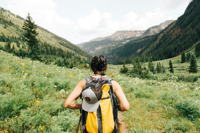 Woman hiking through a green mountain valley