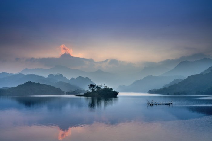 Serene lake with small island and misty mountains