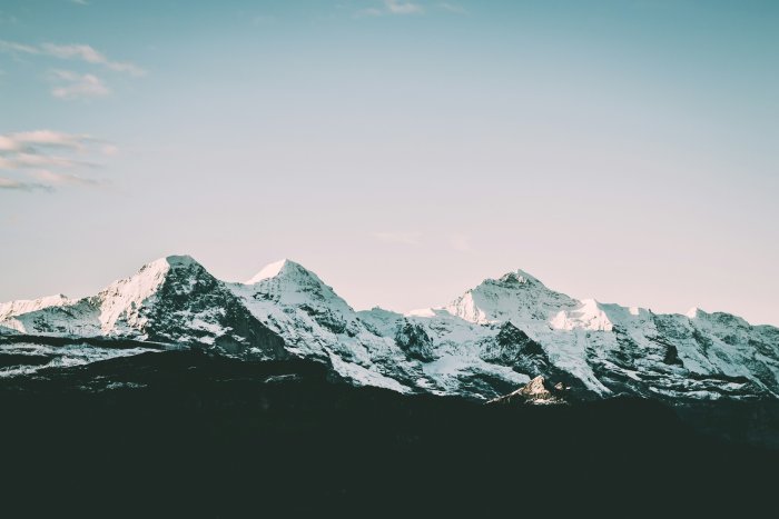 Snow-covered mountain peaks under a pale blue sky