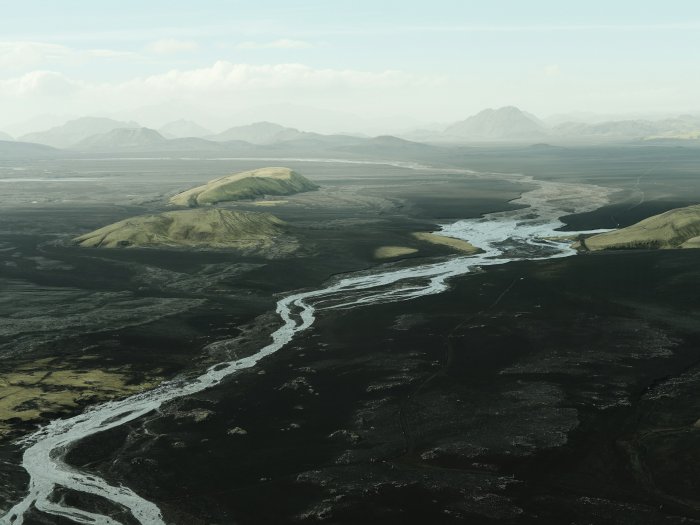Winding river flowing through a dark volcanic landscape
