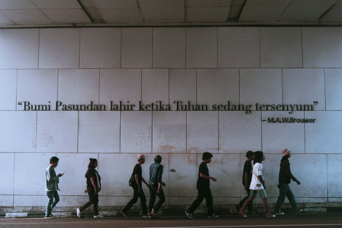 People Walking Past Bumi Pasundan Quote Wall