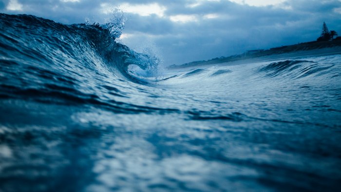 Close-up of a curling ocean wave under cloudy sky