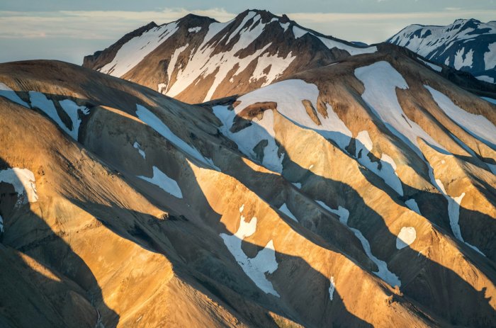 Golden hour sunlight on snow-capped rhyolite mountains